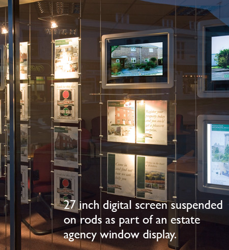 An estate agents window with a 27 inch digital screen suspended on rods as part of the displyay
